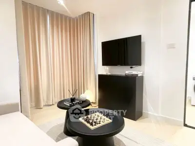 Modern living room with TV, chess set, and stylish decor.