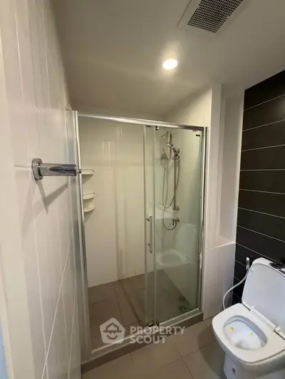 Modern bathroom with glass shower enclosure and sleek fixtures in a contemporary apartment.
