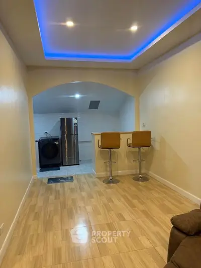 Modern open-plan living area with stylish kitchen and bar seating, featuring sleek lighting and wood flooring.