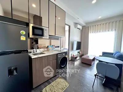 Modern open-layout kitchen and living room with sleek appliances and cozy seating area.
