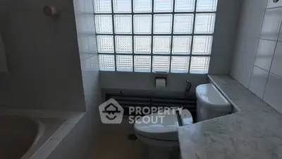 Cozy bathroom with modern toilet and glass block window for natural light