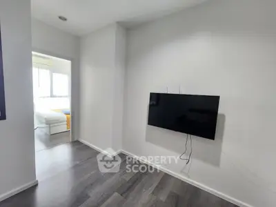 Modern minimalist living room with wall-mounted TV and view into a bright bedroom.