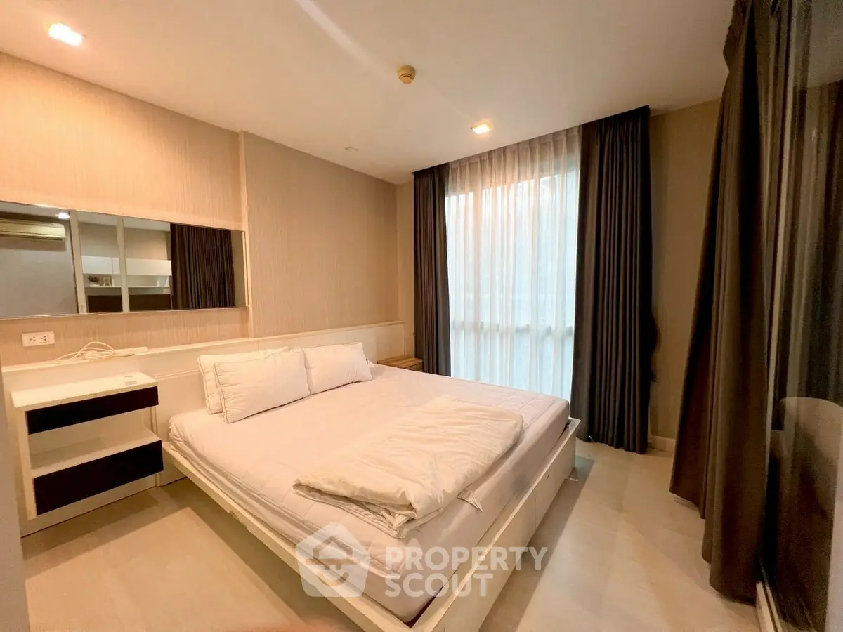 Modern bedroom with large window and elegant curtains in a stylish apartment.