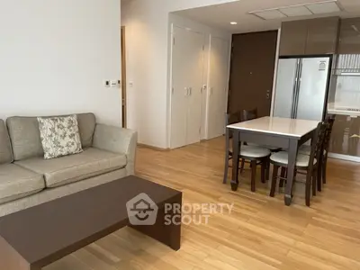 Modern living room with wooden flooring, cozy sofa, dining table, and sleek kitchen appliances.