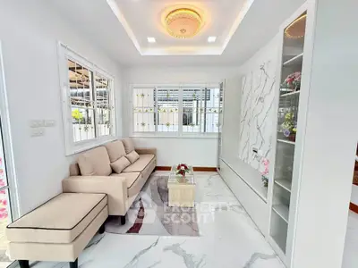Elegant living room with modern decor and large windows, featuring a cozy beige sofa and stylish marble accents.