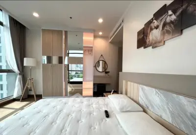 Modern bedroom with large window, stylish decor, and ample natural light in a high-rise apartment.