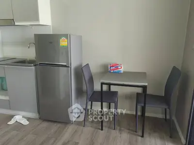 Modern kitchen with sleek fridge and compact dining area in stylish apartment