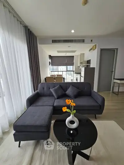 Modern living room with stylish sofa and open kitchen layout in a bright apartment.