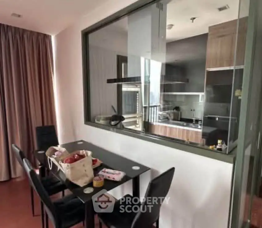 Modern dining area with glass partition overlooking sleek kitchen design