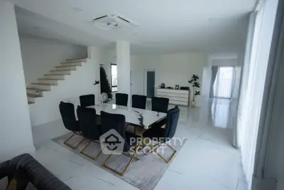 Spacious modern dining room with elegant black chairs and sleek marble table in a bright open-plan layout.