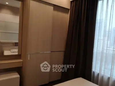 Cozy bedroom with modern wardrobe and large window offering city view.