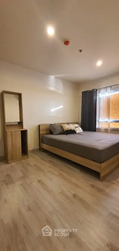 Spacious bedroom with modern wooden bed frame, matching side table, and elegant dark curtains, complemented by warm-toned laminate flooring.