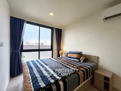 Modern bedroom with large window and stylish bedding in a cozy apartment.