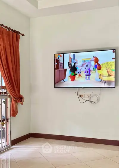 Spacious living room with mounted TV and elegant curtains, perfect for family entertainment.
