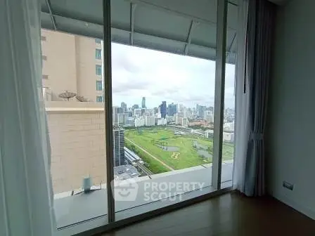 Stunning cityscape view from a high-rise apartment window, showcasing urban skyline and green spaces.