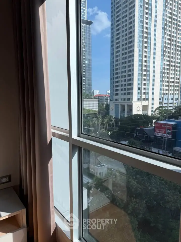 Spacious apartment window with cityscape view, offering natural light and urban living experience.
