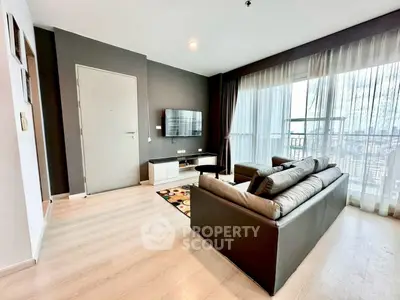Modern living room with sleek furniture and large windows offering city views.