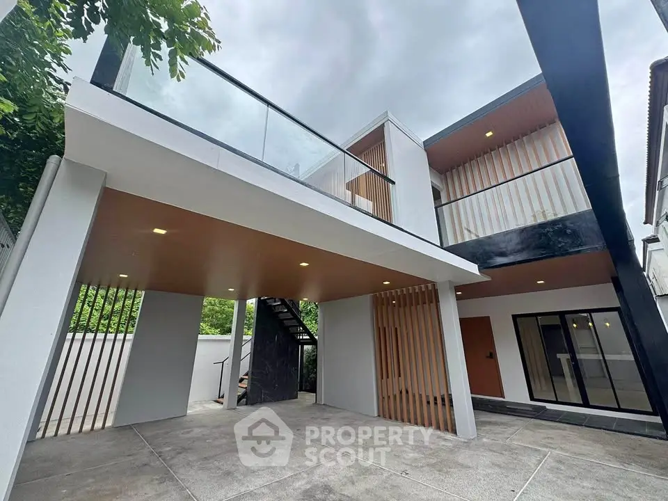 Modern two-story home with sleek design and spacious outdoor area, featuring glass railings and contemporary architecture.
