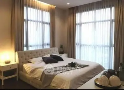 Elegant bedroom with large windows and stylish decor, perfect for relaxation and comfort.
