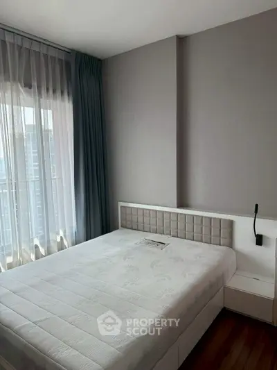 Modern bedroom with stylish decor and large window offering city views.