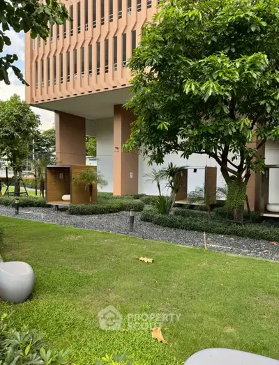 Modern building exterior with lush garden and contemporary design elements.
