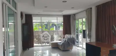 Spacious living room with large windows and garden view, perfect for relaxation and natural light.