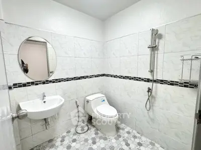 Modern bathroom with white tiles, round mirror, and shower area