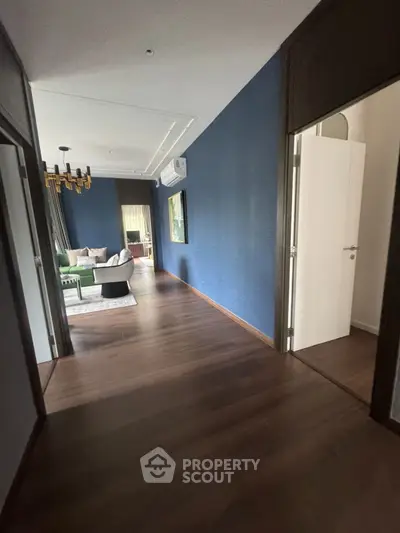 Elegant hallway leading to a stylish living room with modern decor and wooden flooring.