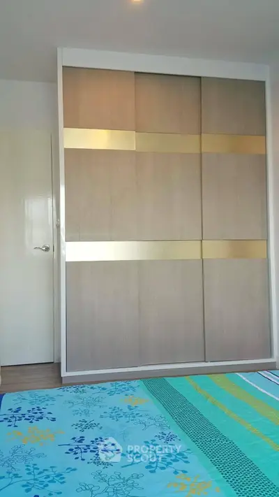 Modern bedroom with stylish wardrobe and colorful bedding