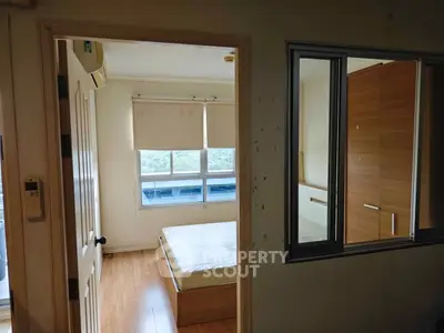 Cozy bedroom with large window and wooden flooring, perfect for natural light lovers.