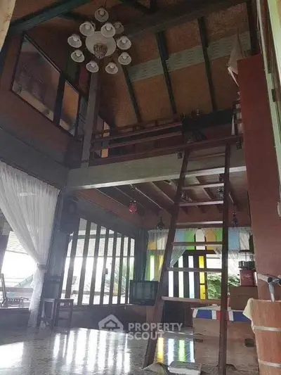 Charming rustic living room with high ceilings and loft, featuring wooden beams and large windows.