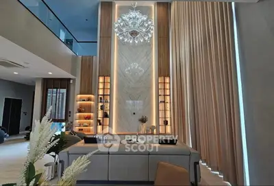 Luxurious living room with high ceilings, elegant chandelier, and modern decor