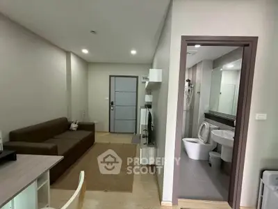 Modern apartment interior with cozy living room and adjacent bathroom, featuring sleek design and neutral tones.