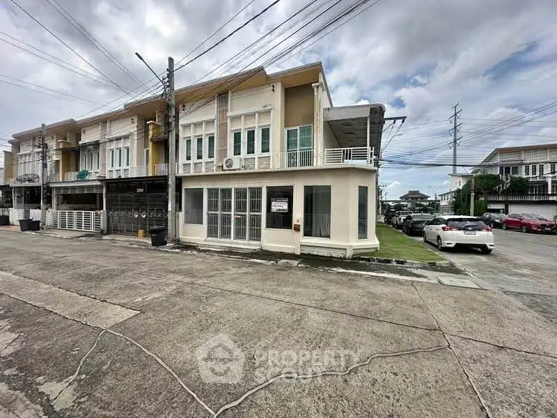Modern corner townhouse with large windows and spacious outdoor area in a suburban neighborhood.