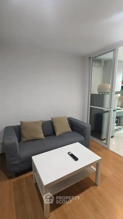 Cozy living room with modern sofa and coffee table, featuring a sleek open layout and wooden flooring.