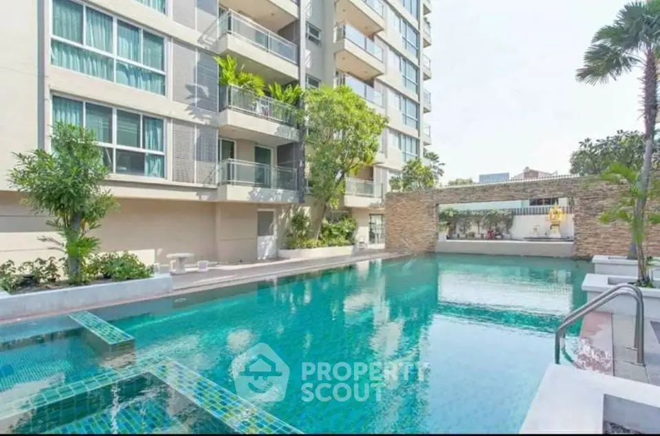 Luxurious apartment building with a stunning outdoor pool and lush greenery.