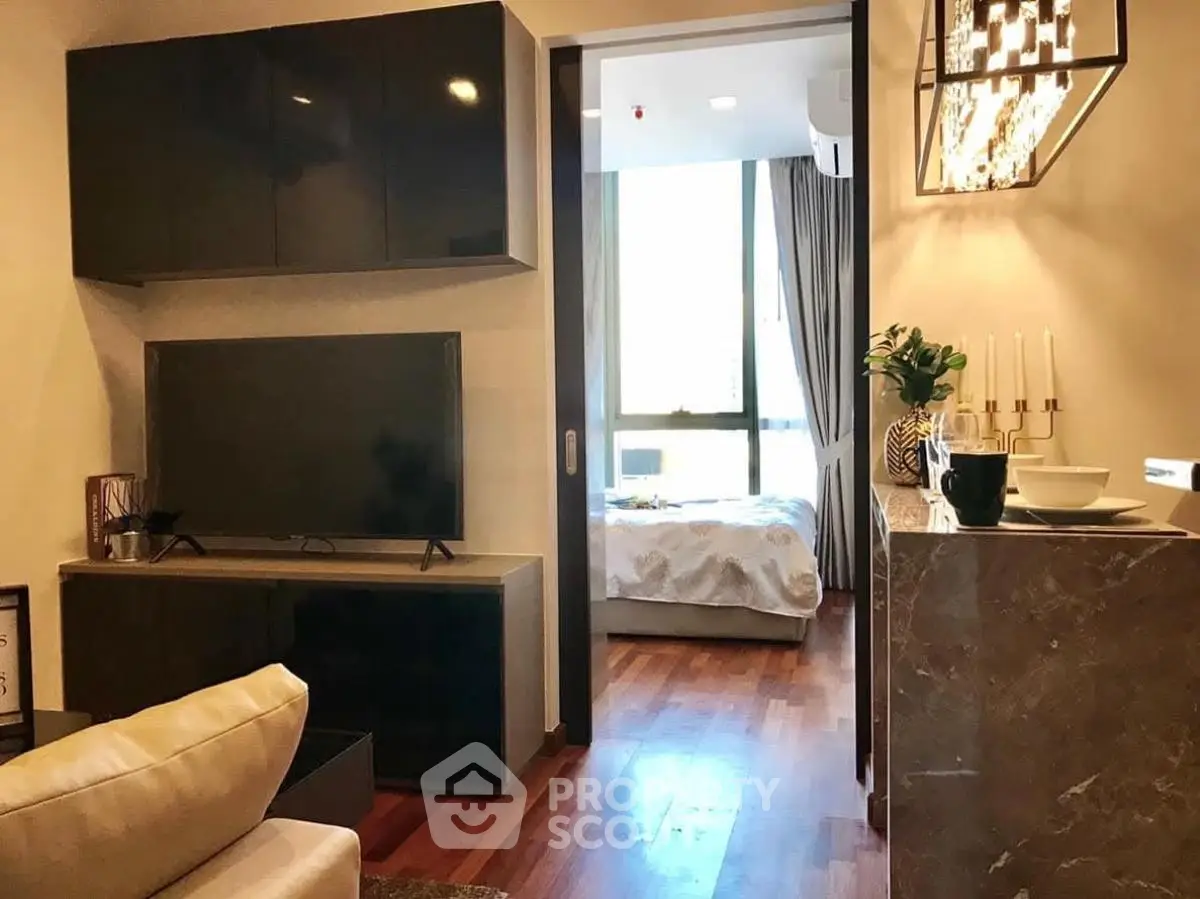 Modern living room with sleek TV unit and view into cozy bedroom