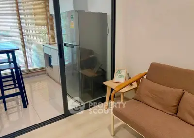 Modern apartment with cozy living area and sleek kitchen featuring a stainless steel fridge.