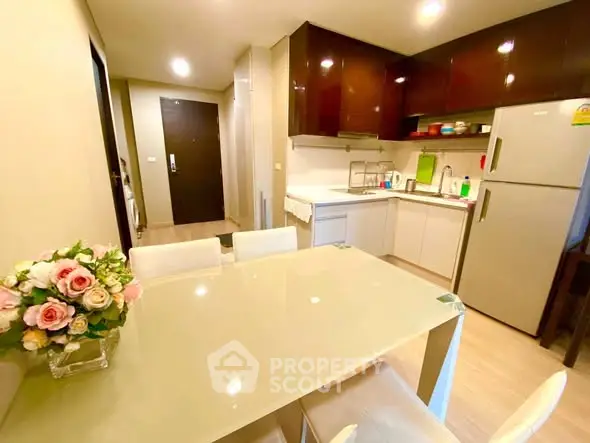 Modern kitchen with dining area, featuring sleek cabinetry and stainless steel appliances.