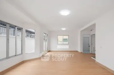 Spacious unfurnished room with large windows and wooden flooring, perfect for customization.