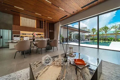 Luxurious open-plan living room with pool view, modern kitchen, and elegant decor.