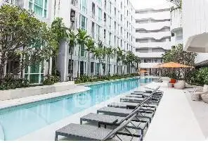 Luxurious modern apartment complex with stunning poolside view and lush greenery.