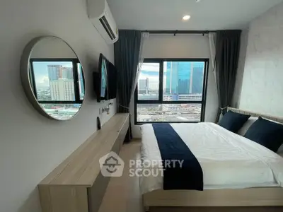 Modern bedroom with city view, featuring sleek furniture and large windows for natural light.