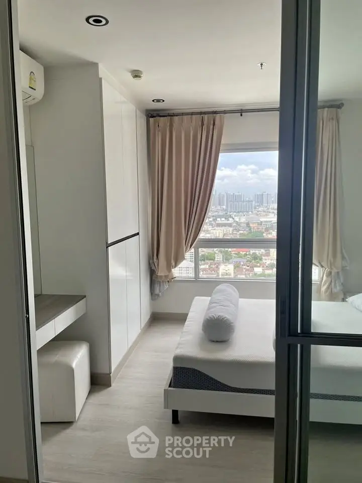 Modern bedroom with city view, featuring sleek white furniture and large window for natural light.