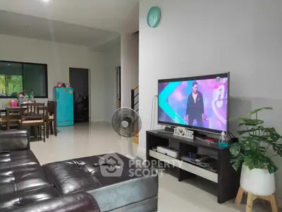 Spacious living room with large leather sofa, modern entertainment unit, and an open layout leading to a dining area.