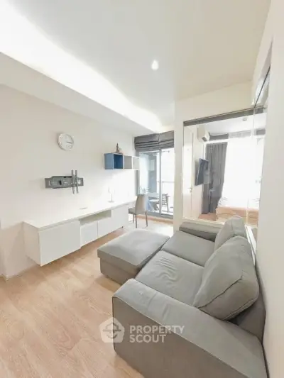 Modern living room with sleek furniture and natural light, featuring a cozy gray sofa and stylish decor.