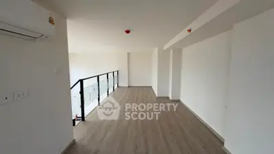 Spacious modern interior with wooden flooring and sleek railing, perfect for versatile use.