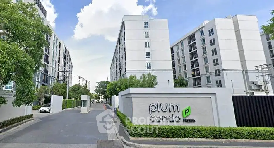 Modern condo building exterior with lush greenery and clear blue sky.