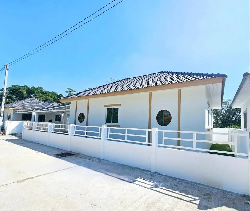 Modern single-story house with white exterior and tiled roof in a serene neighborhood.