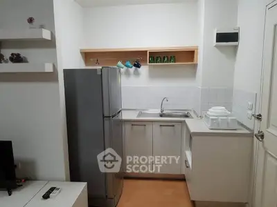 Modern compact kitchen with sleek cabinetry and stainless steel fridge in a cozy apartment.